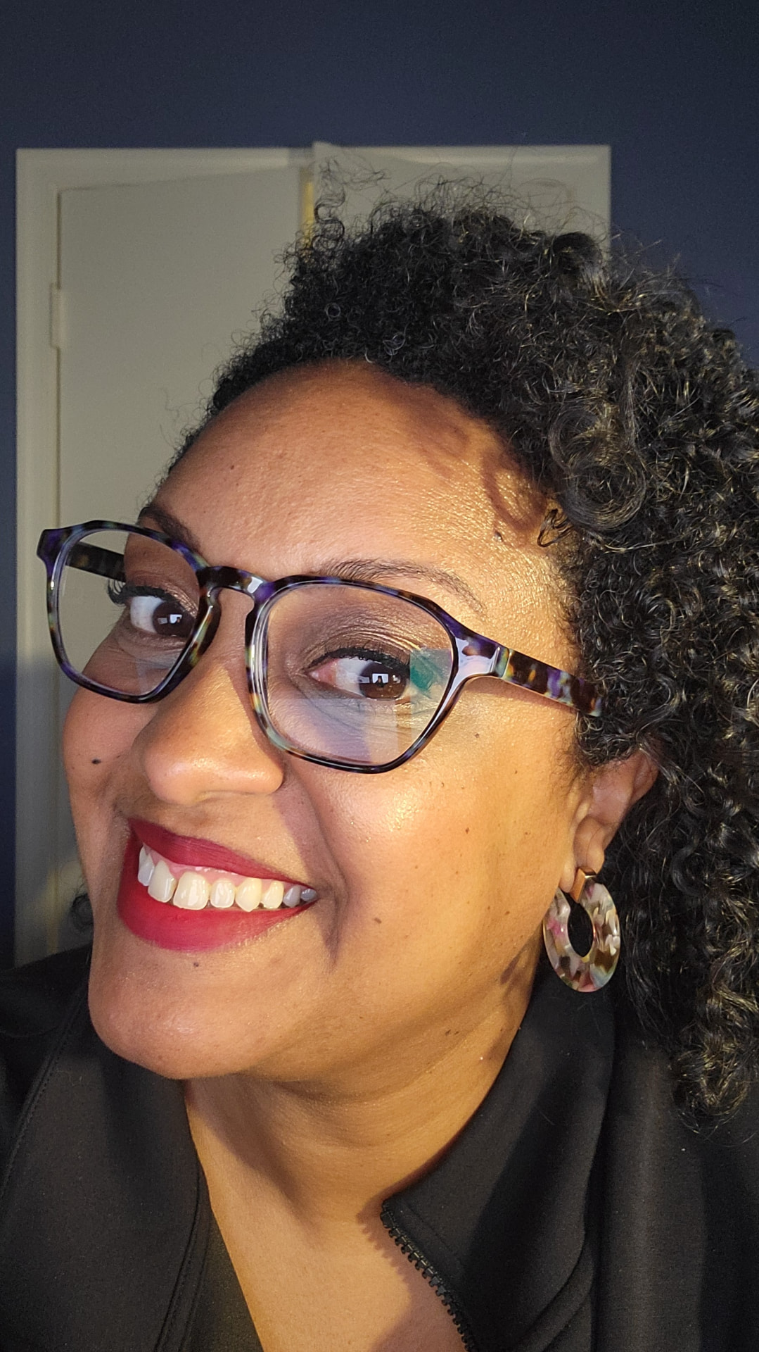 Jolana smiling, wearing tortoiseshell glasses